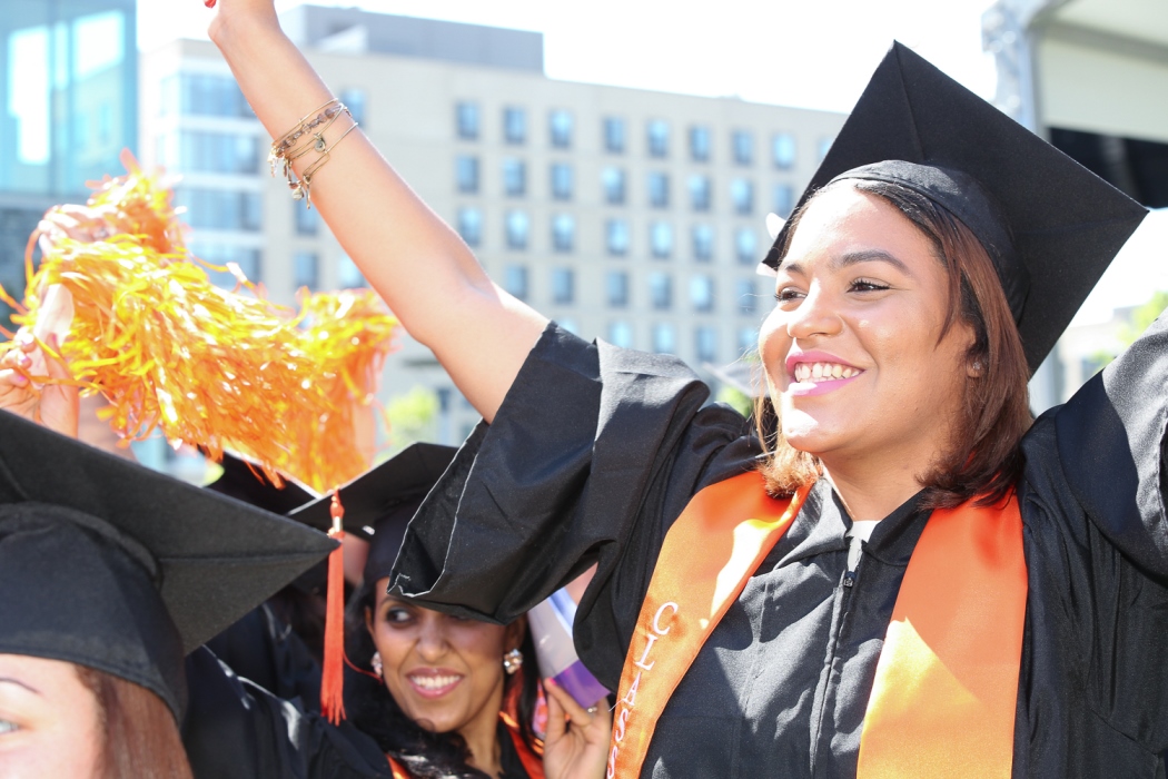 Photo of young women at commencement waving pom poms