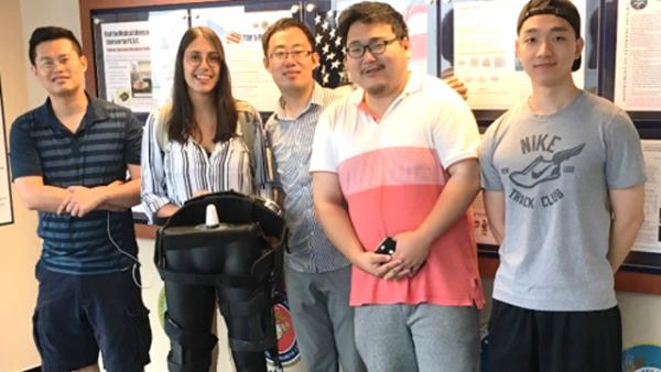 CCNY Mechanical Engineering Professor Hao Su [third from left] with members of his research team and a model of their exoskeleton.