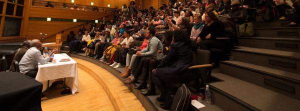 Chinua Achebe Legacy Series talking to a full theater of students 