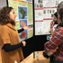 Two students looking at poster while listening too other student