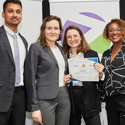 Photo of 4 people standing and one is holding an award