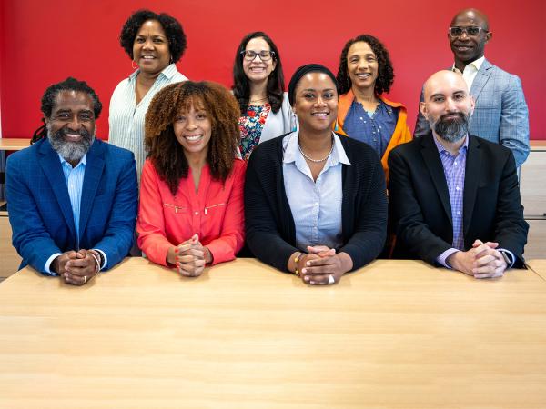 8 Colin Powell School Academic Advisors sitting in and smiling for a group photo.