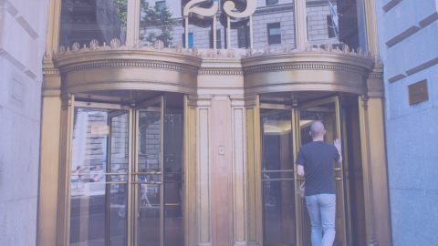 25 Broadway entrance showing two revolving doors with a male entering on the right side.